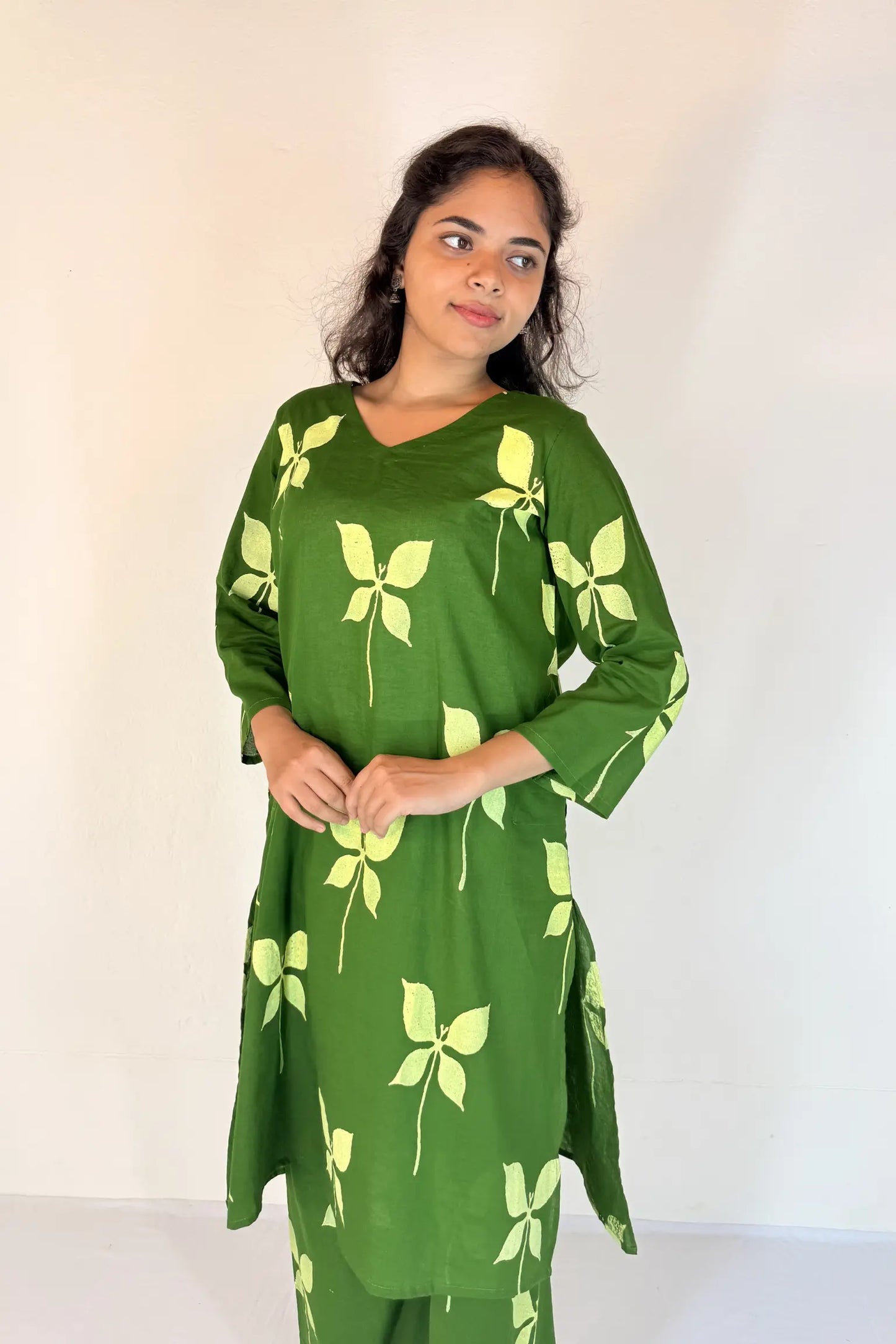 Woman wearing a green dress with leaf patterns against a white background