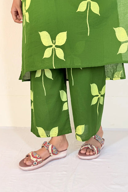 Green outfit with leaf patterns and sandals on a white background