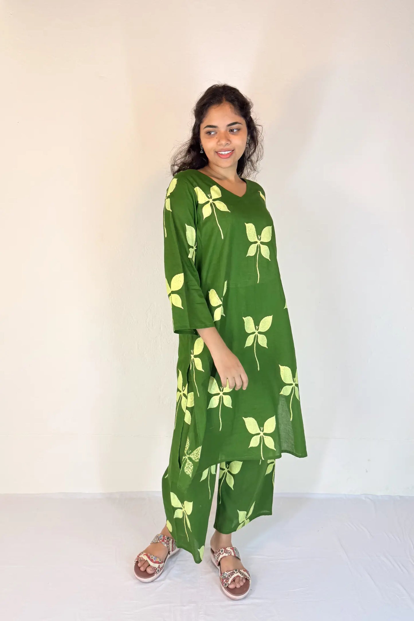 Woman wearing a green dress with floral patterns against a white background