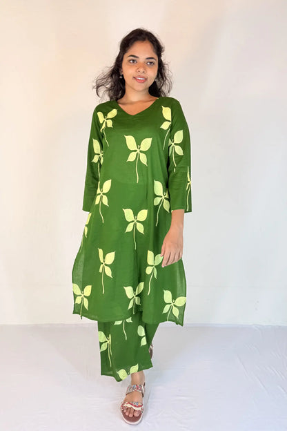 Woman wearing a green dress with yellow leaf patterns on a white background