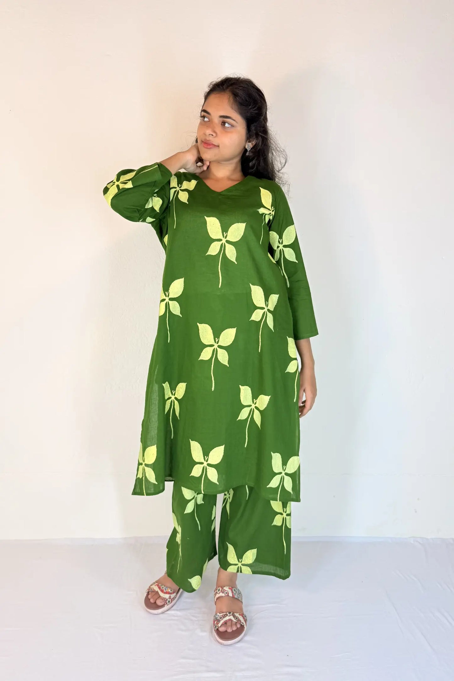 Woman wearing a green outfit with leaf patterns against a white background