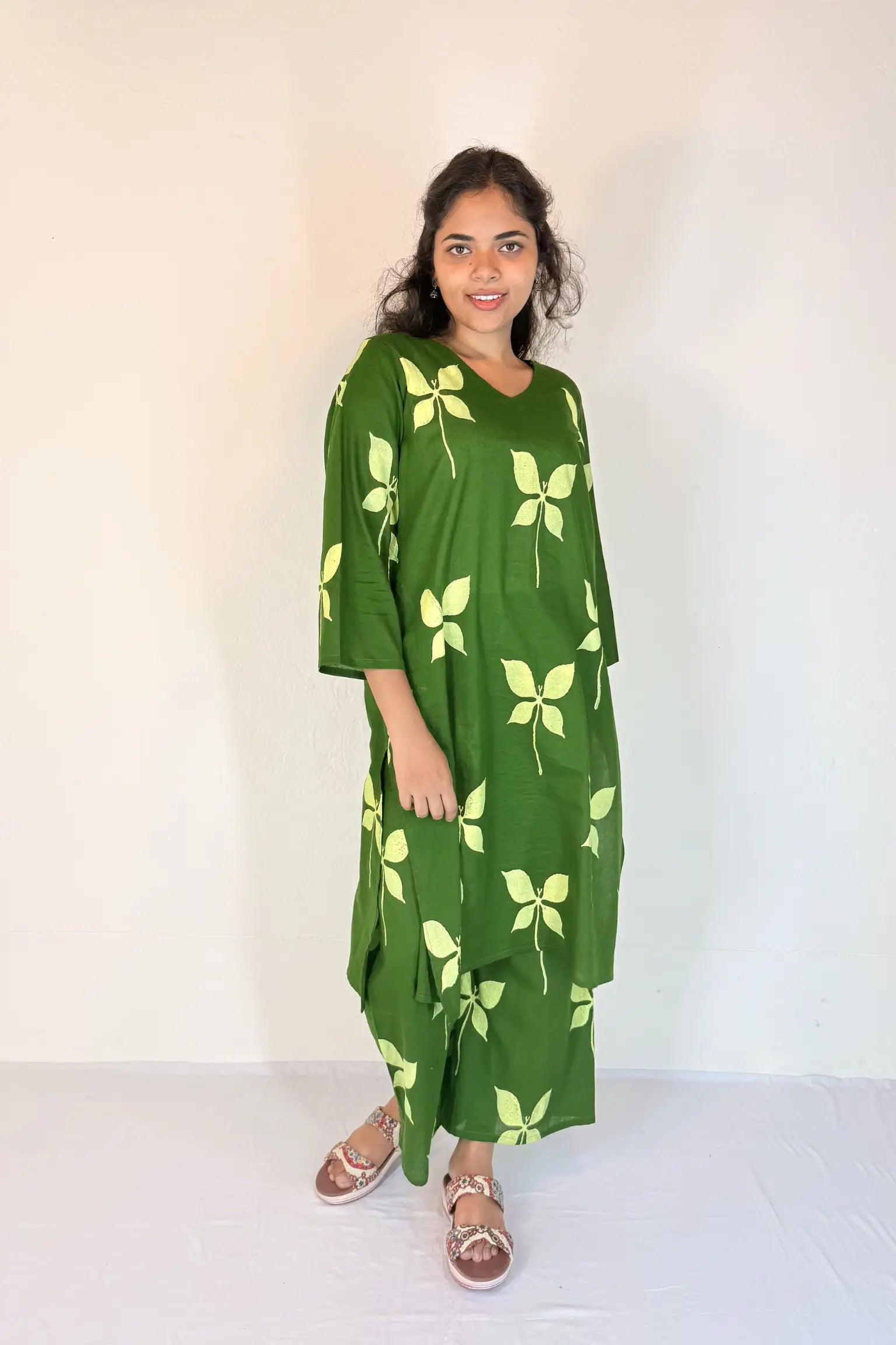 Woman wearing a green dress with leaf patterns against a white background