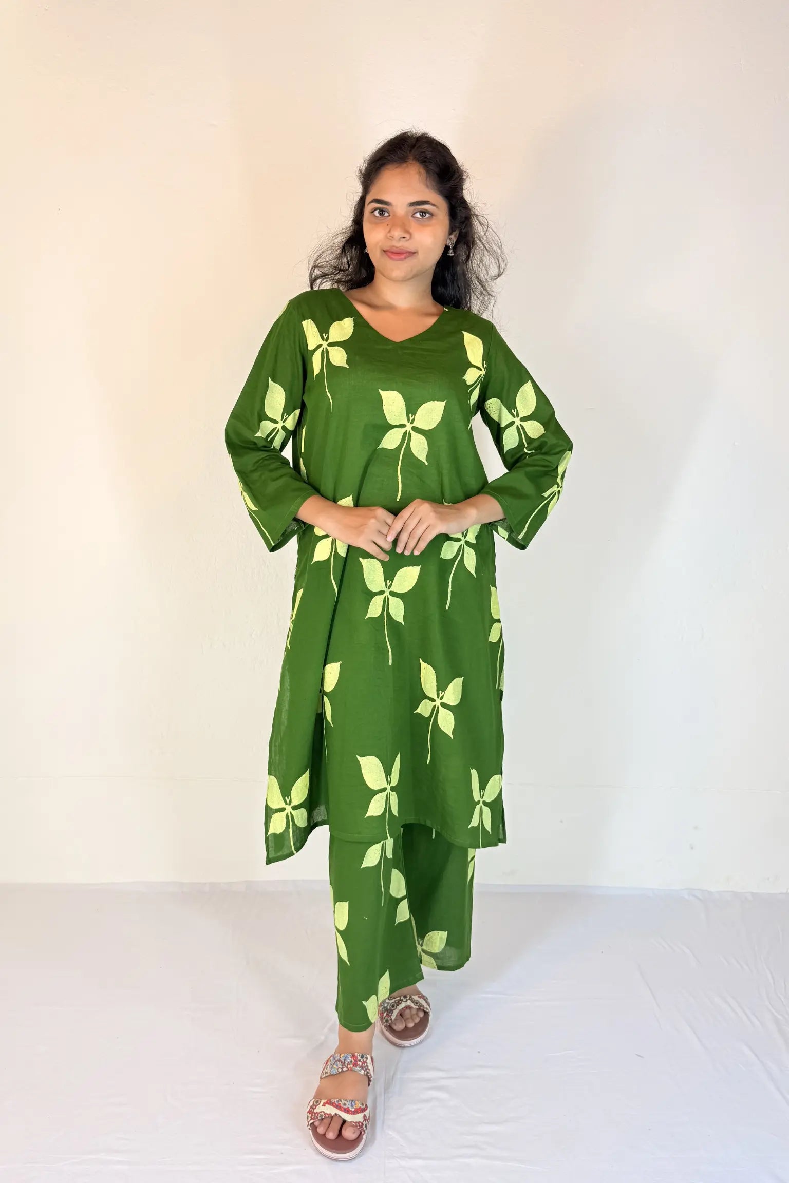 Woman wearing a green dress with leaf patterns on a white background