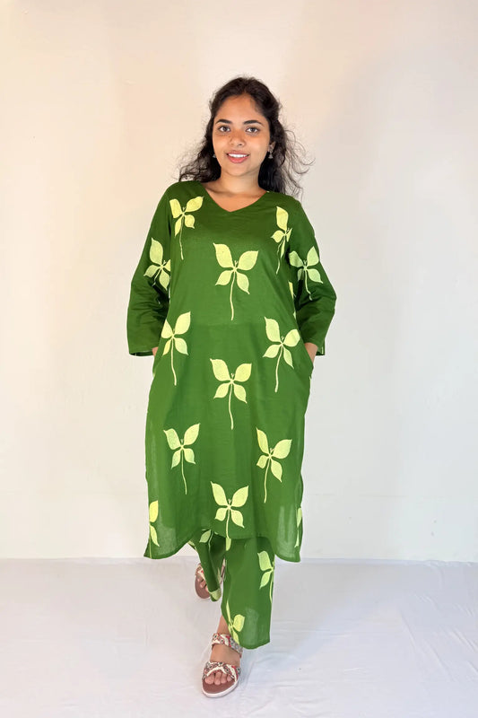 Woman wearing a green dress with yellow floral patterns on a white background