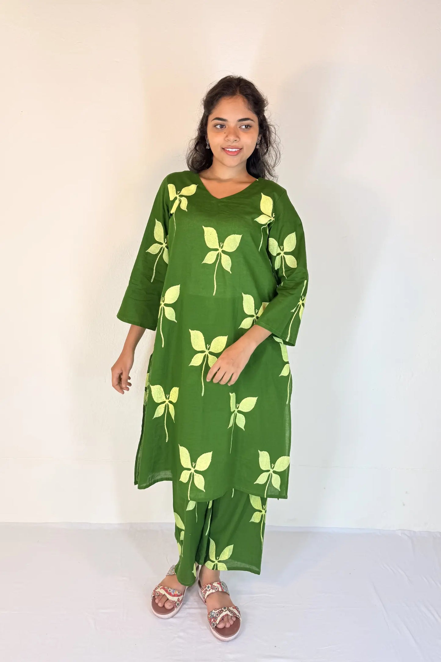 Woman wearing a green dress with leaf patterns on a white background