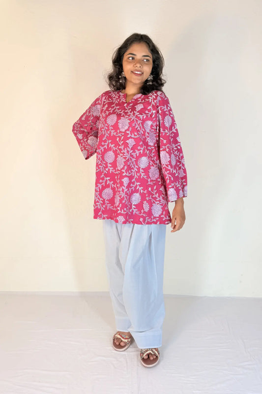 Woman wearing a pink floral top and light blue pants on a white background
