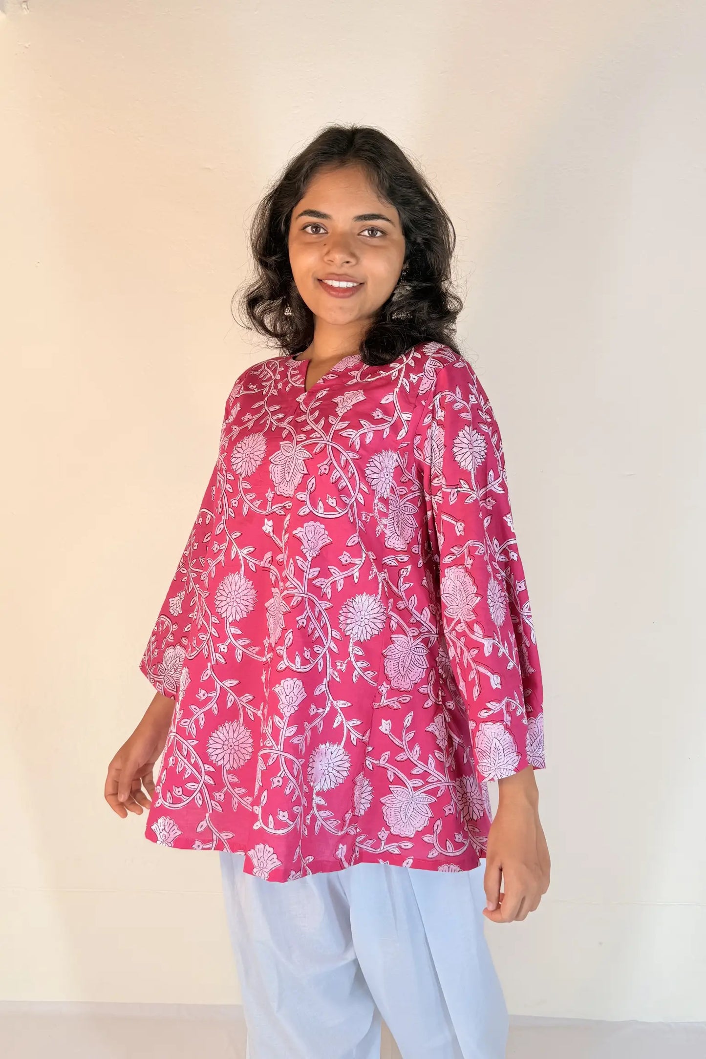 Woman wearing a pink floral blouse against a plain background