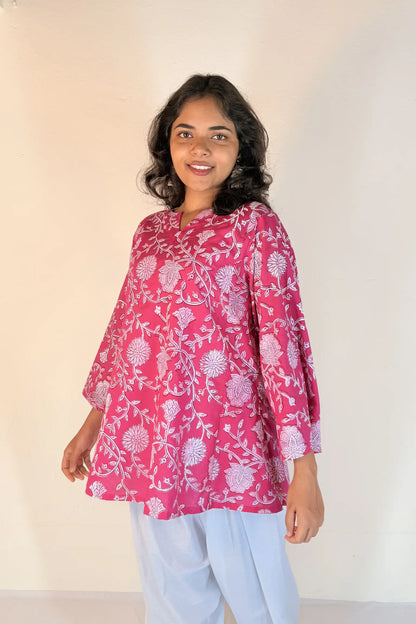 Woman wearing a pink floral blouse against a plain background