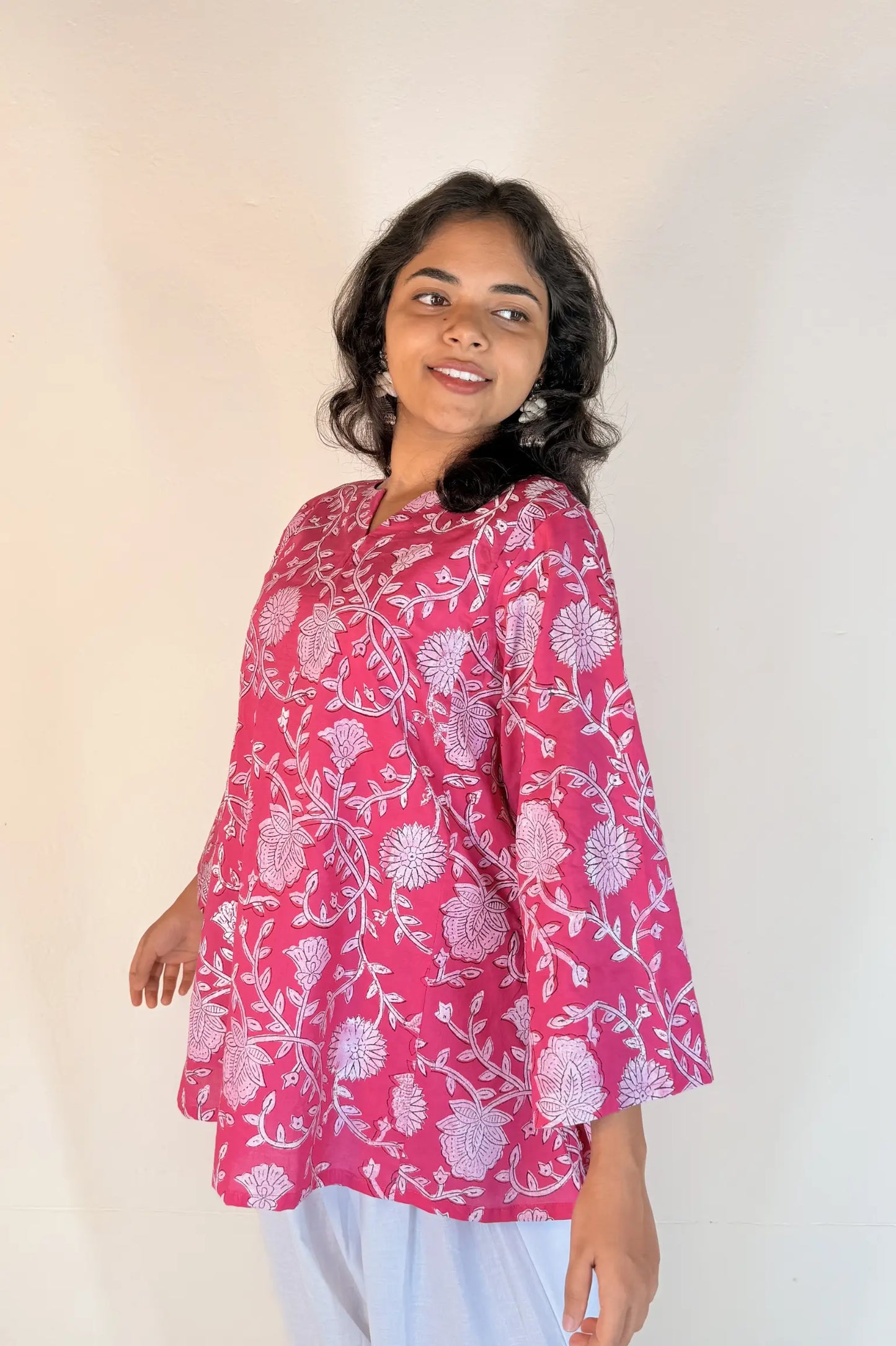 Woman wearing a pink floral patterned top against a plain background