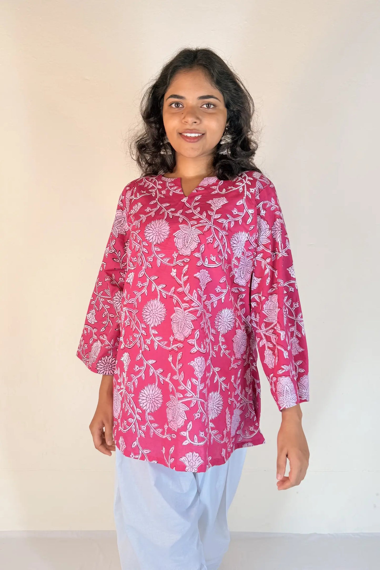 Woman wearing a pink floral blouse against a plain background