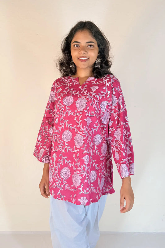 Woman wearing a pink floral blouse against a plain background