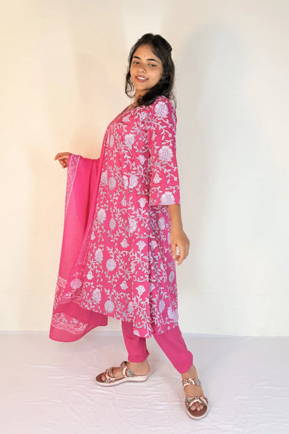 Woman wearing a pink traditional outfit with a white floral pattern on a plain background
