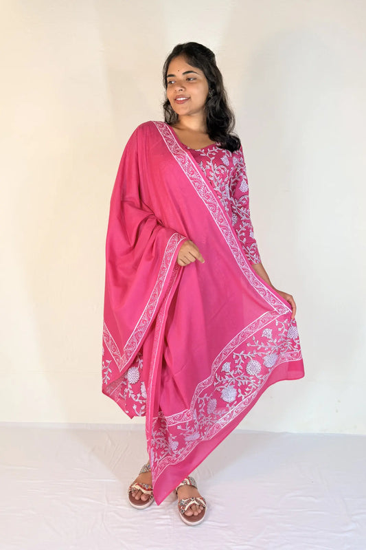 Woman wearing a pink saree with white patterns on a plain background