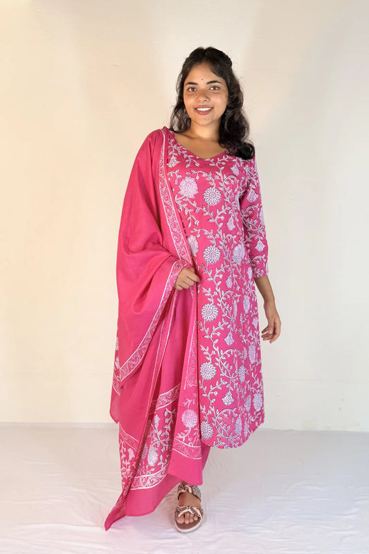 Woman wearing a pink traditional outfit with white patterns on a plain background