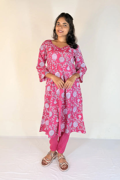 Woman wearing a pink floral kurta with matching pants against a white background