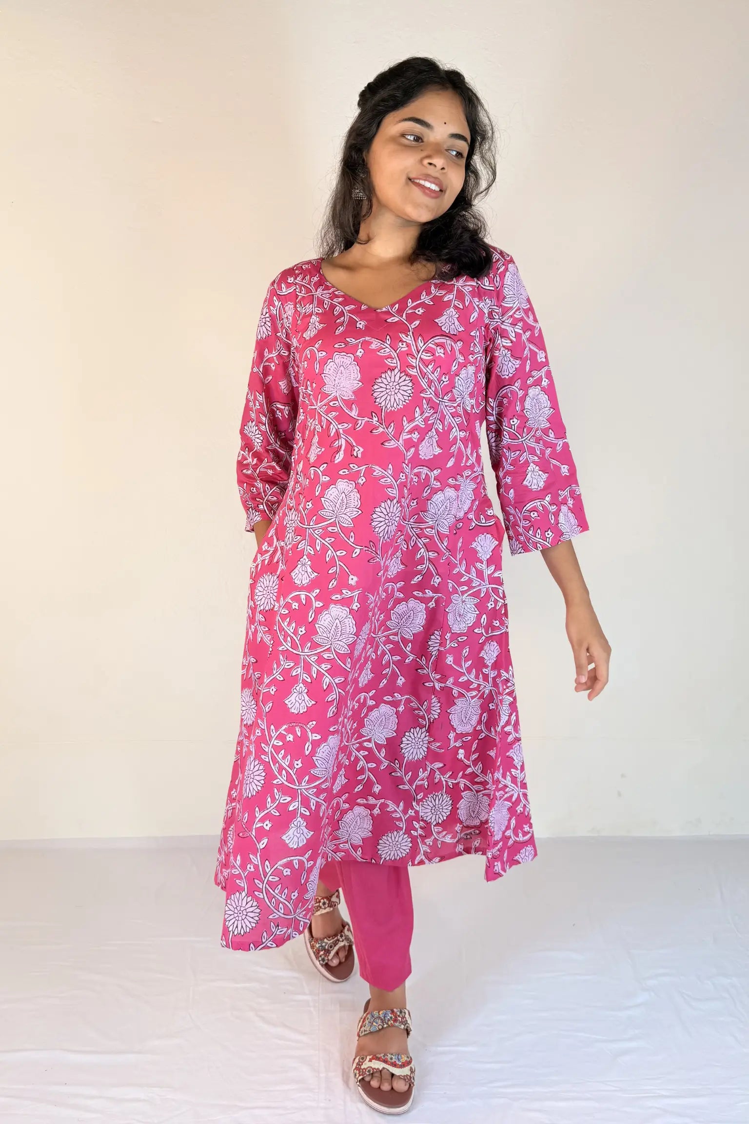 Woman wearing a pink floral kurta with pink pants on a white background
