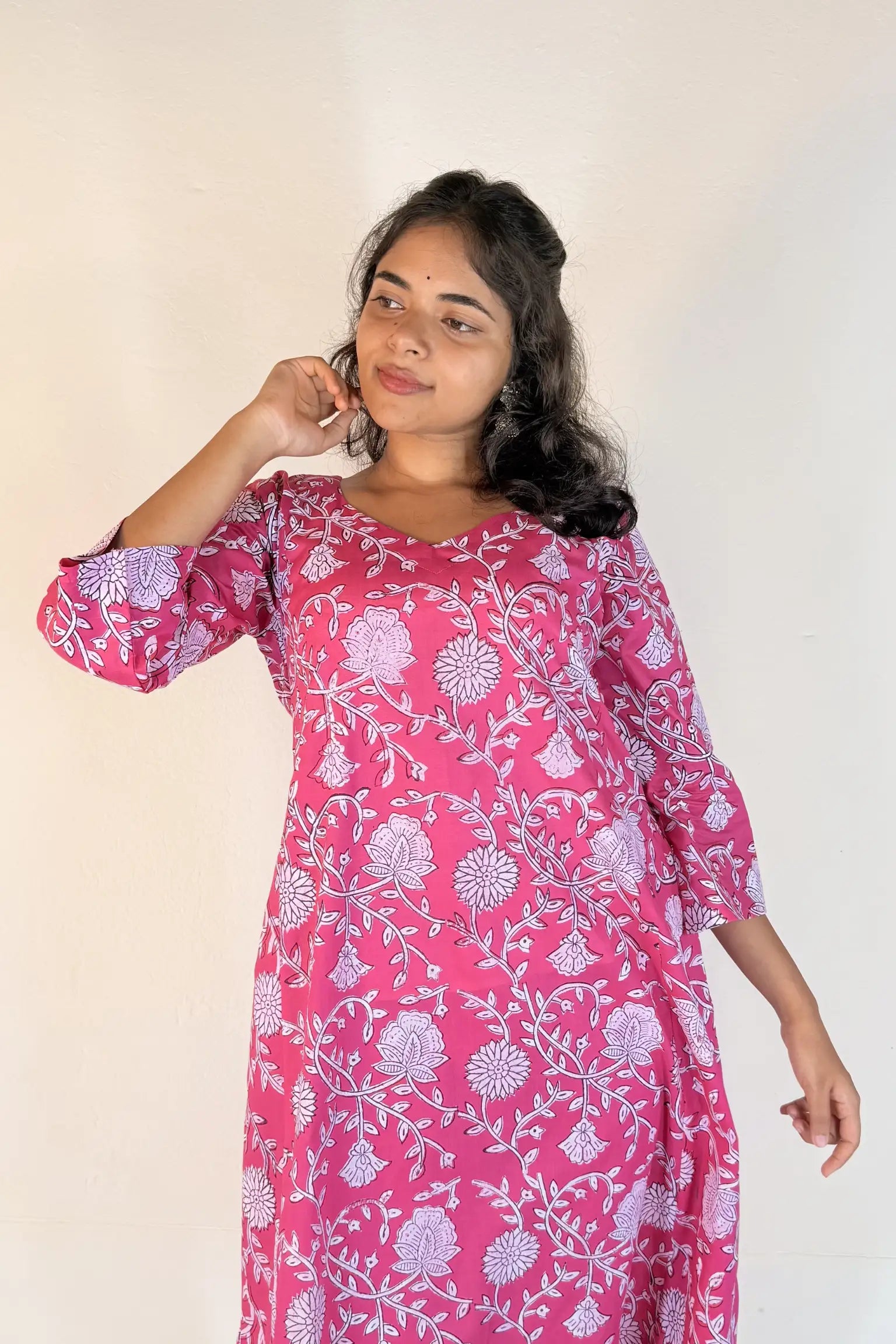 Woman wearing a pink floral dress against a white background