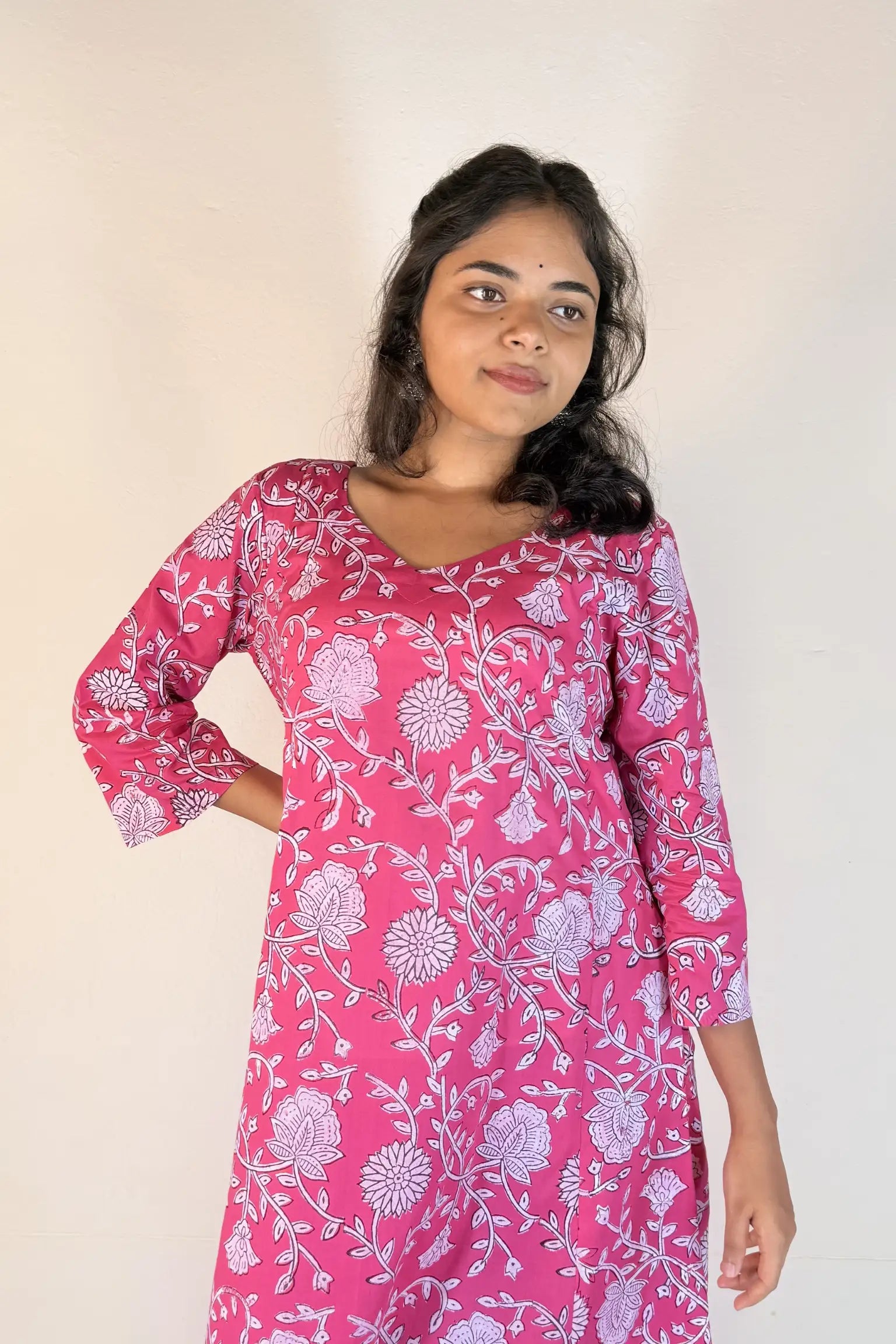 Woman wearing a pink floral dress against a plain background
