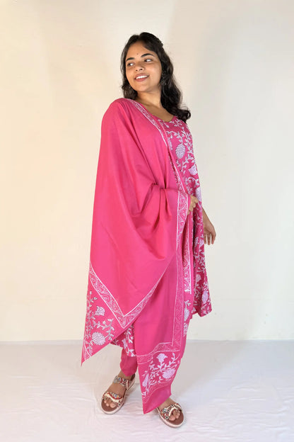 Woman wearing a pink traditional outfit with white patterns on a plain background