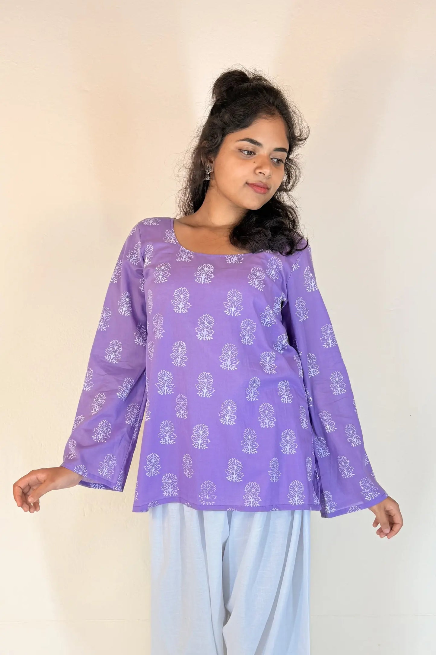 Woman wearing a purple top with white patterns on a plain background
