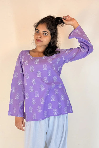 Woman wearing a purple top with white patterns on a plain background