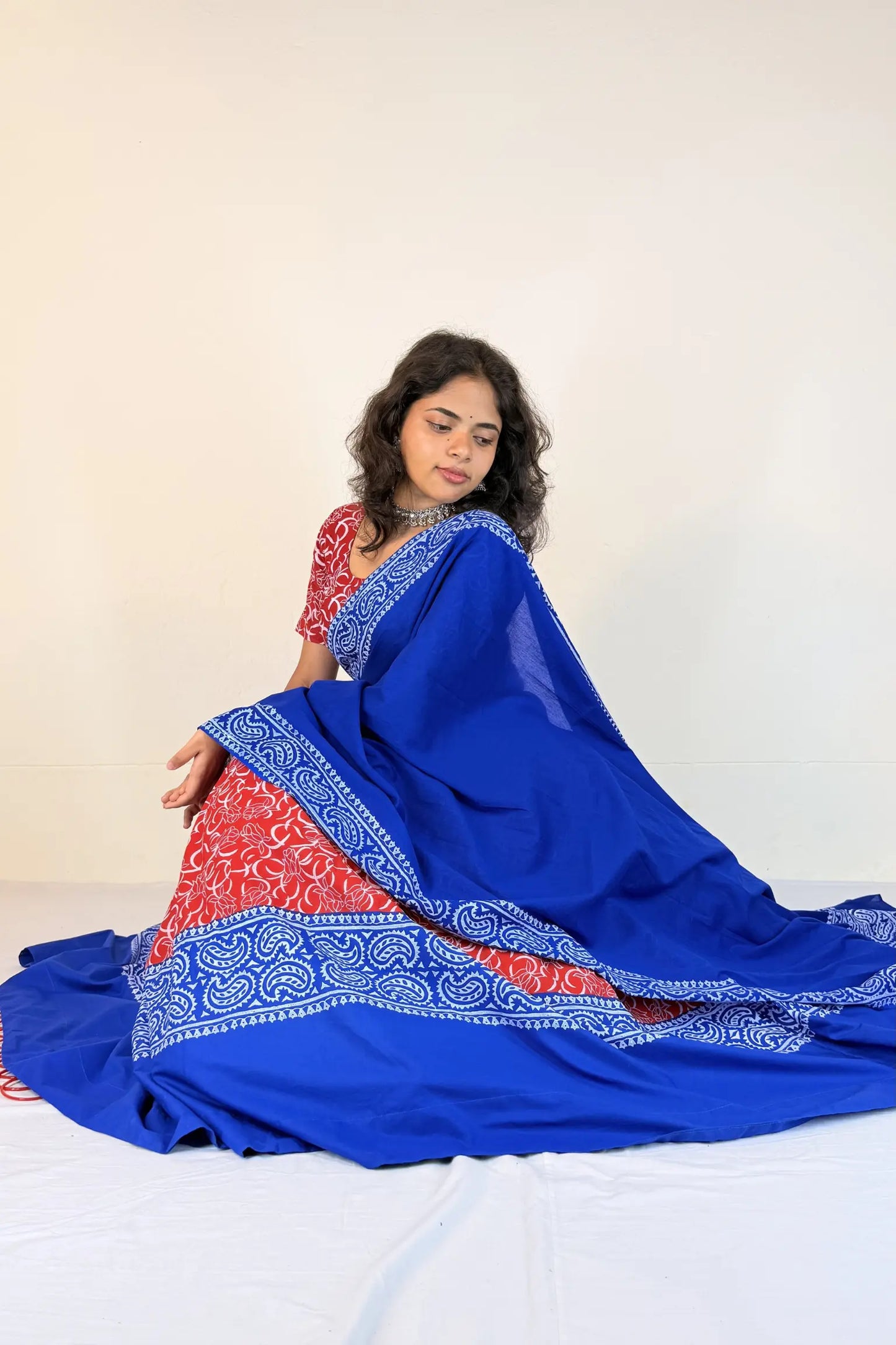 Woman wearing a blue and red traditional outfit with a white background
