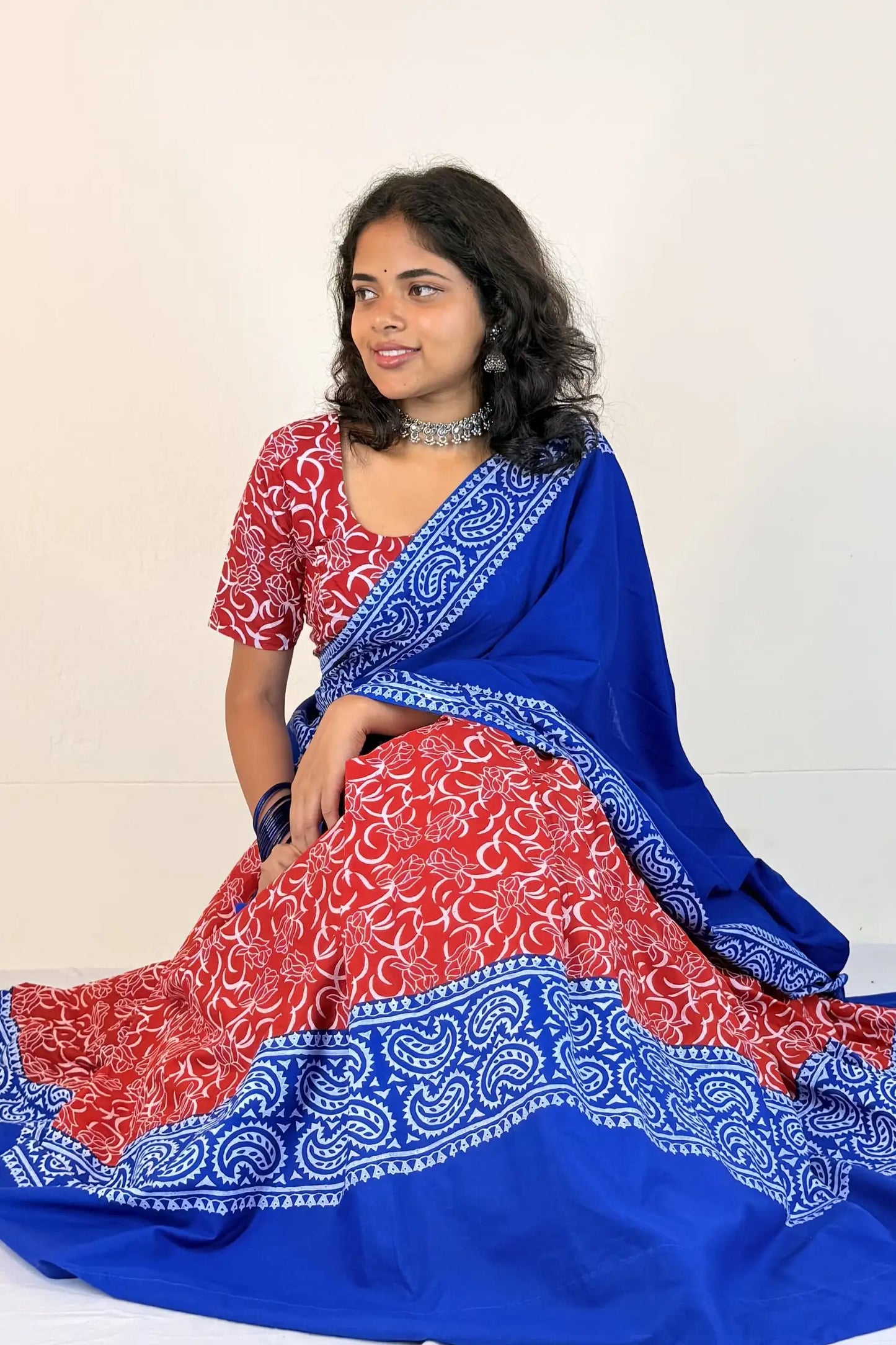 Woman wearing a red and blue Gopi Dress with a white background