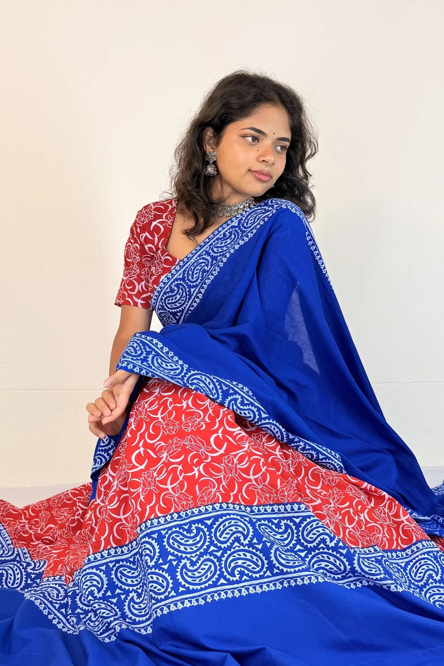 Woman wearing a blue and red traditional outfit with a white background