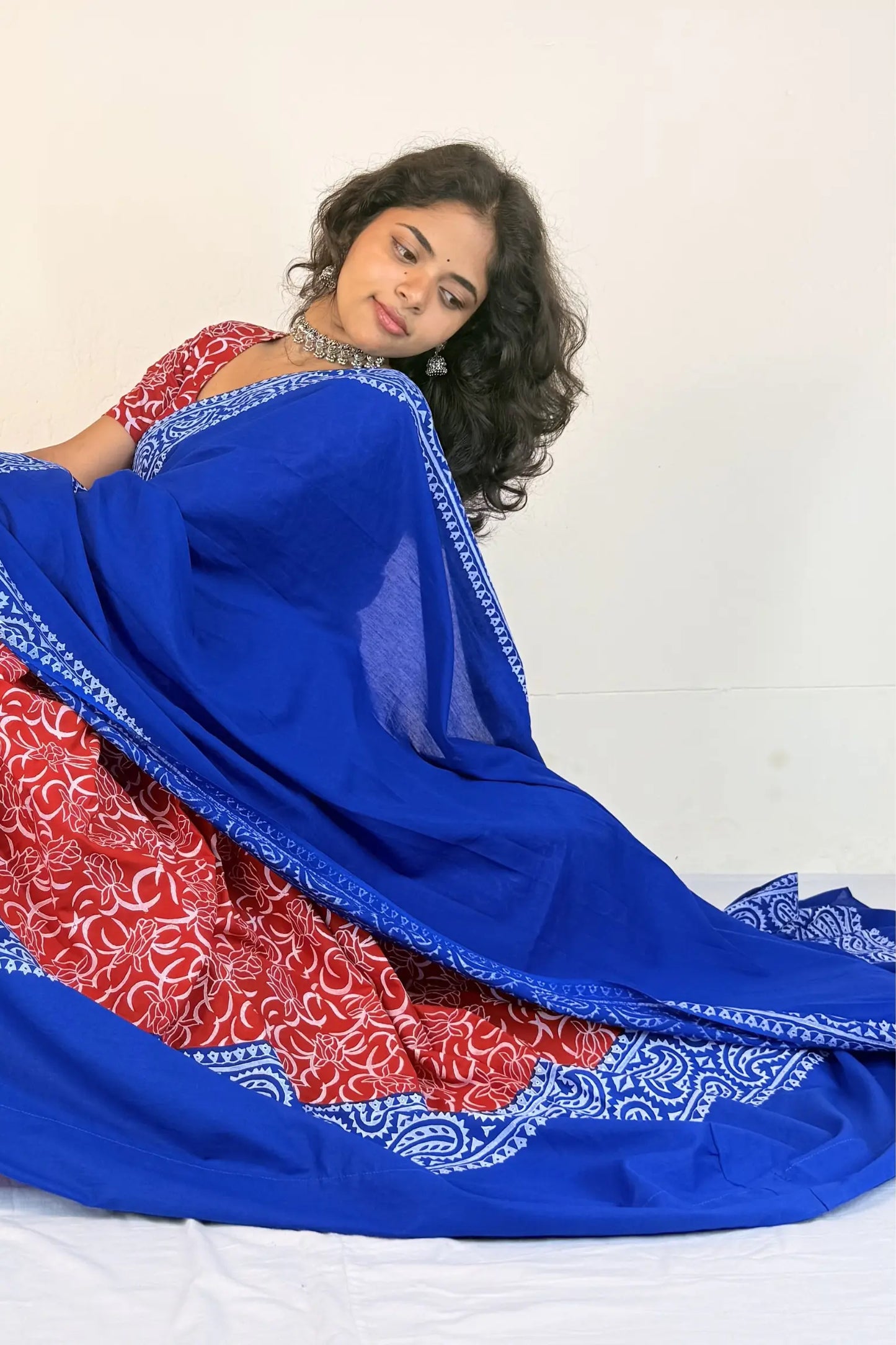 Woman wearing a blue and red traditional outfit with a white background