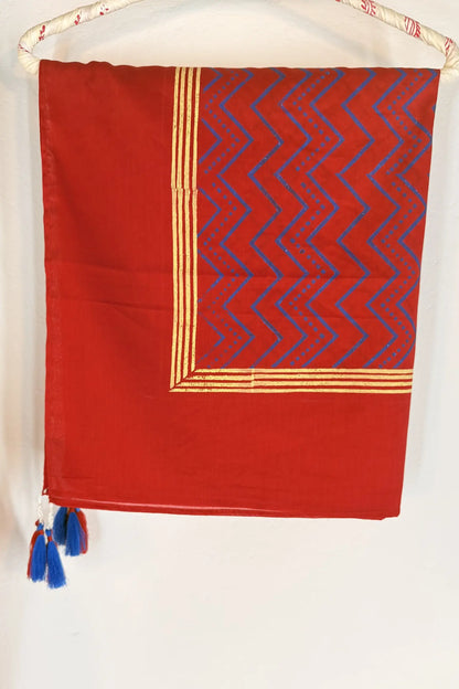 Red cotton scarf with geometric block print in brown and gold, featuring fine line detailing and handcrafted tassels