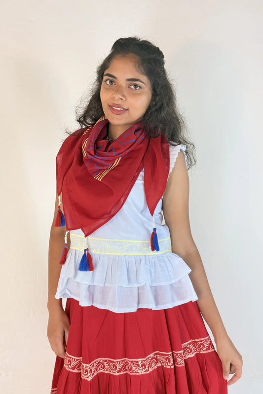 Woman wearing a red and white traditional outfit with a scarf on a plain background