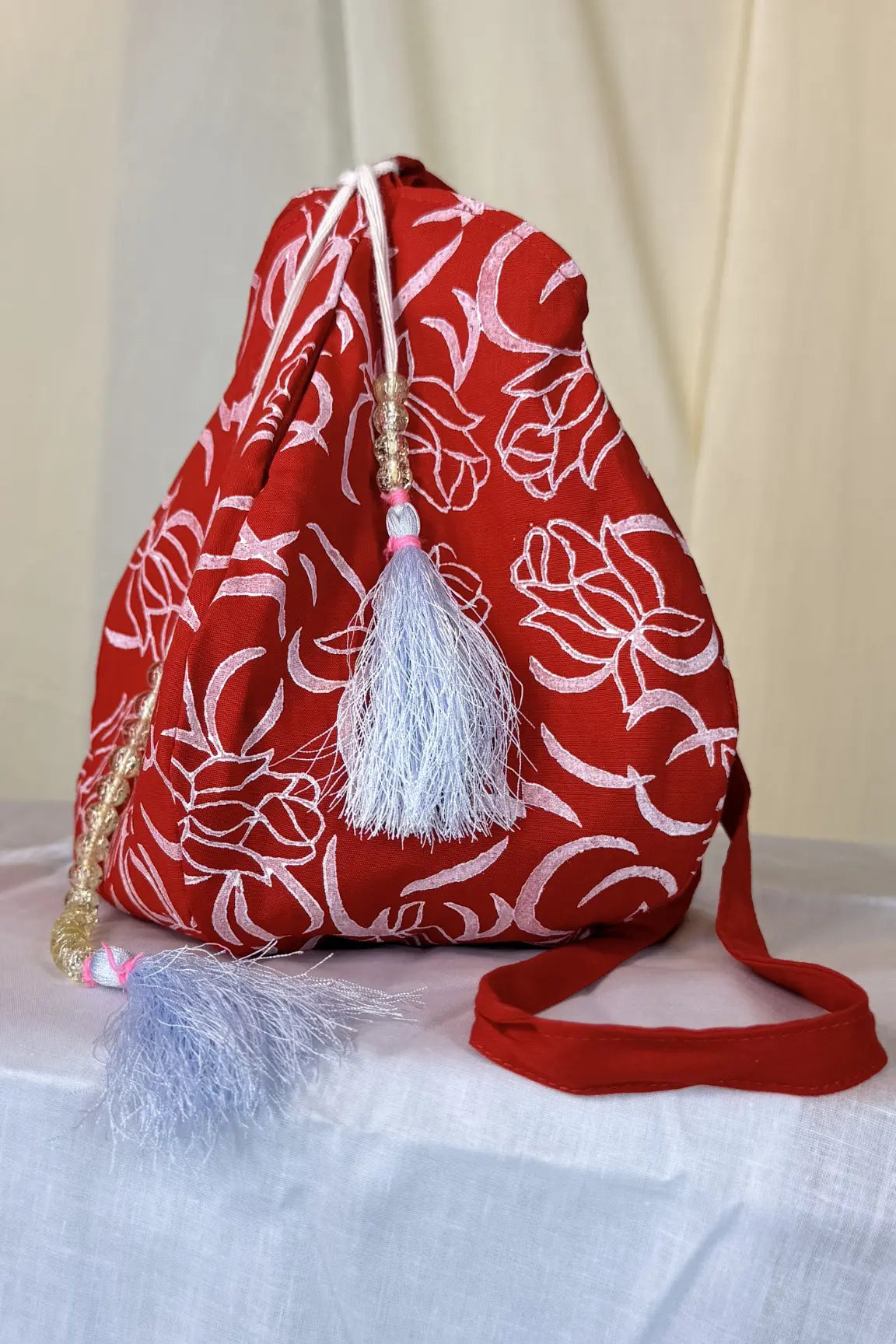 Red drawstring bag with white floral pattern on a light background