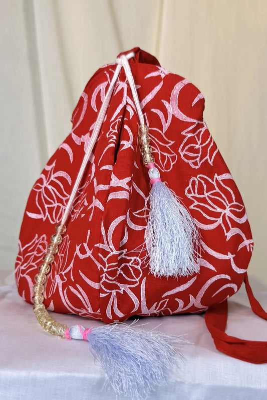 Red drawstring bag with white floral pattern on a light background