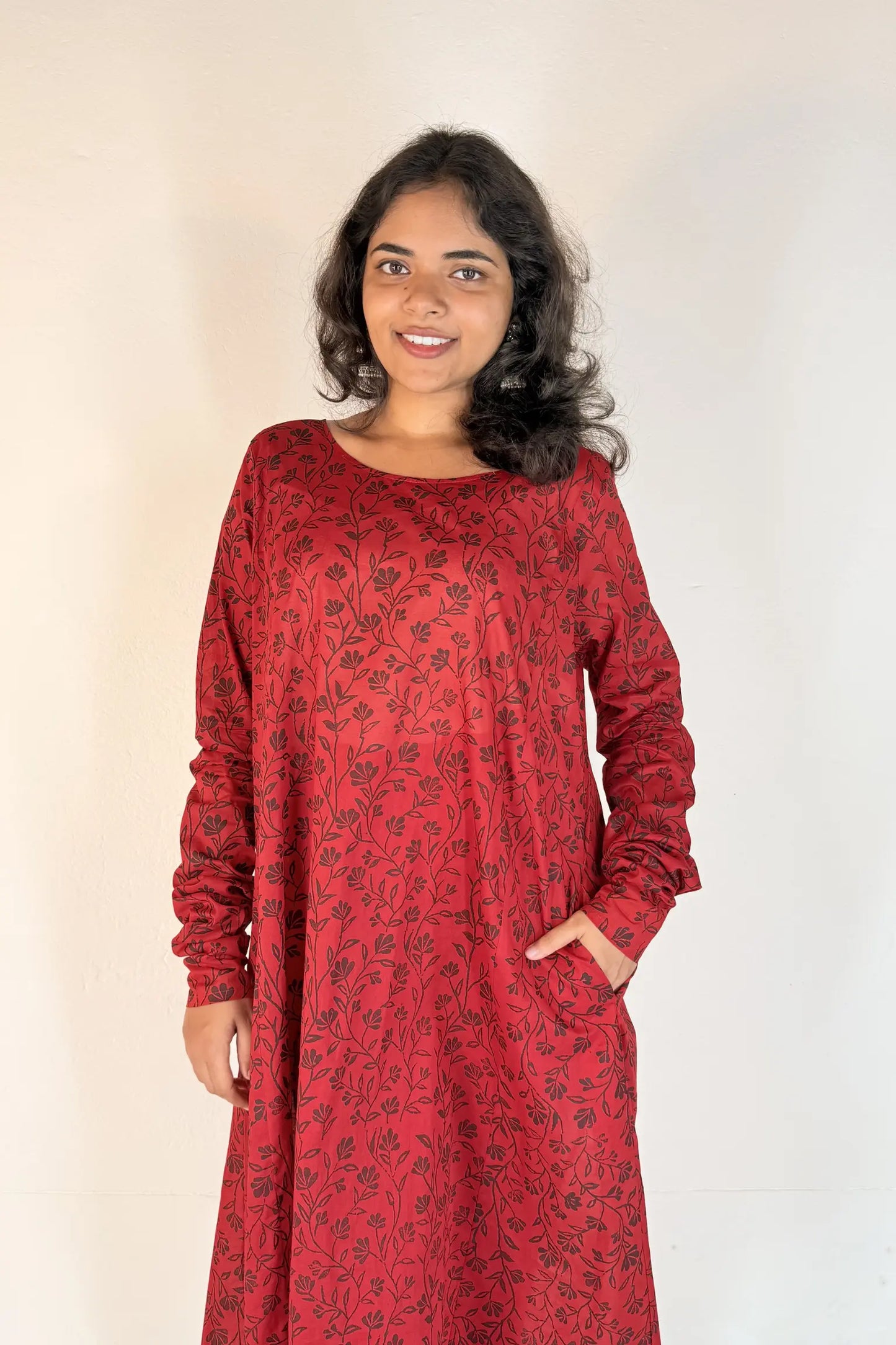 Woman wearing a red dress with a pattern against a plain background