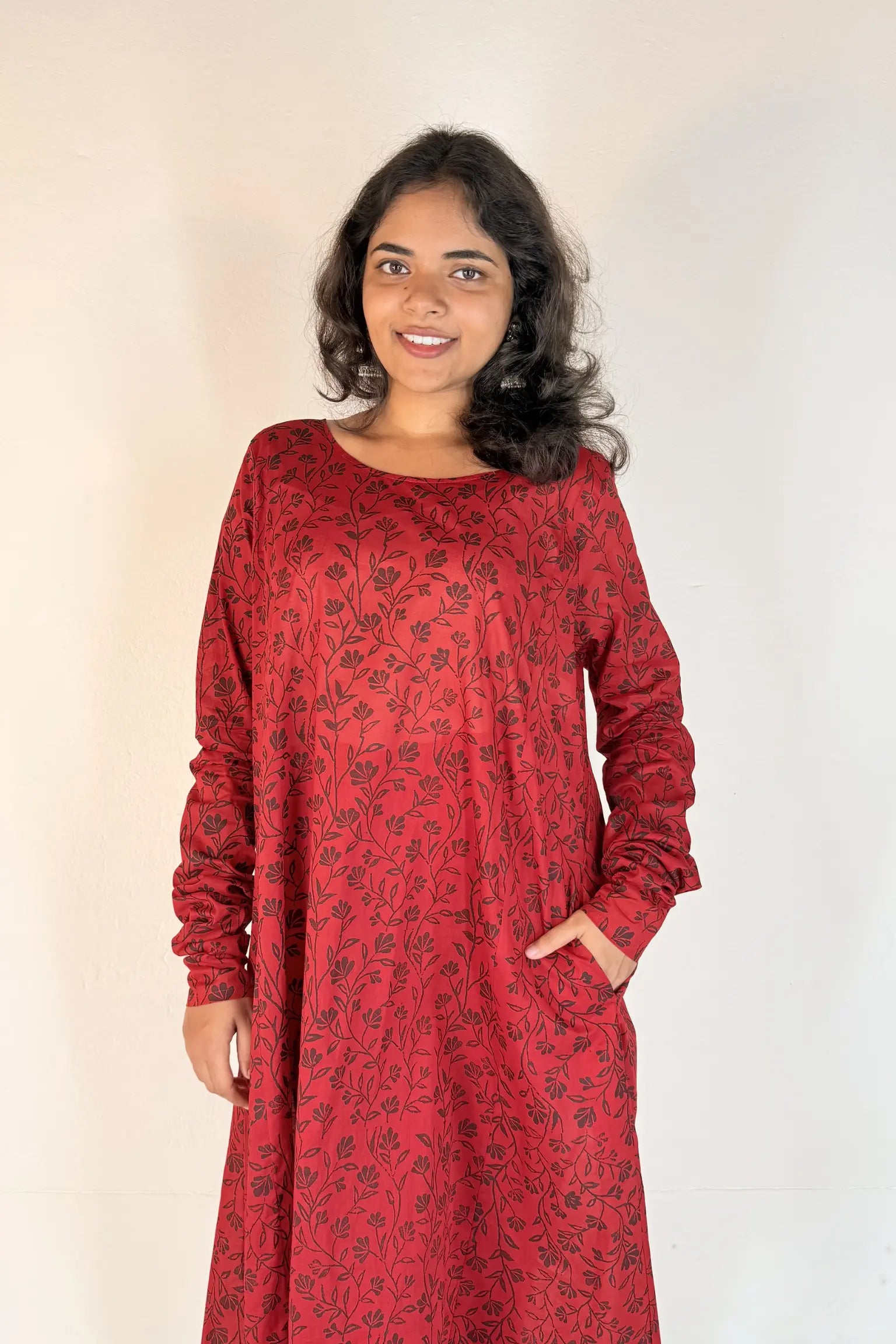 Woman wearing a red dress with a pattern against a plain background