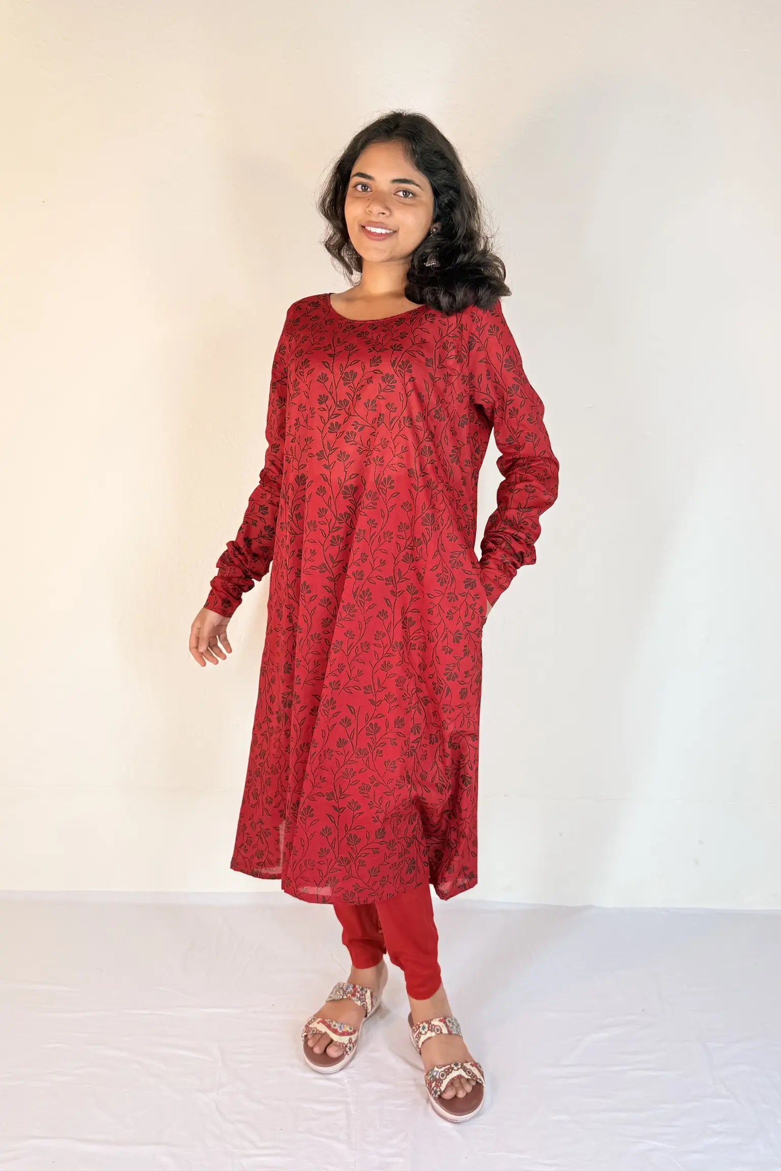 Woman wearing a red patterned dress with a plain background