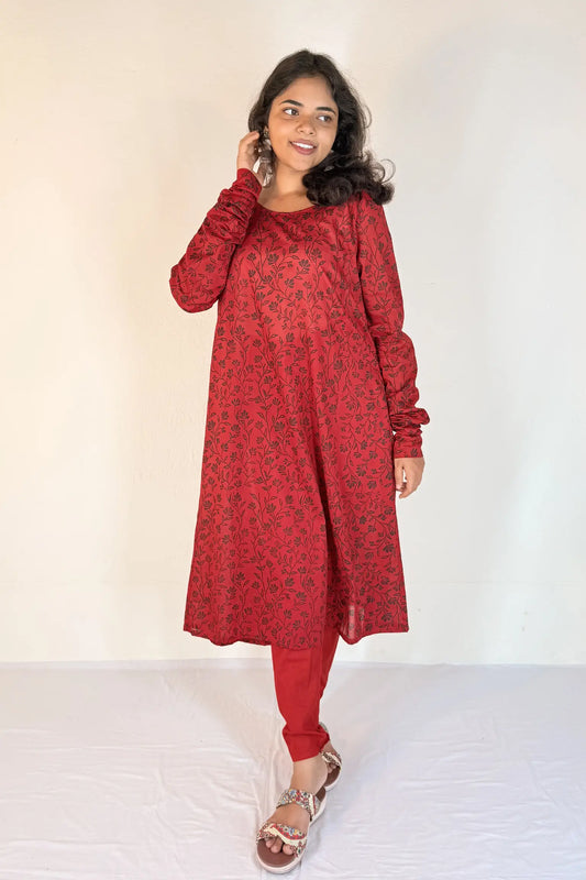 Woman wearing a red patterned outfit against a white background