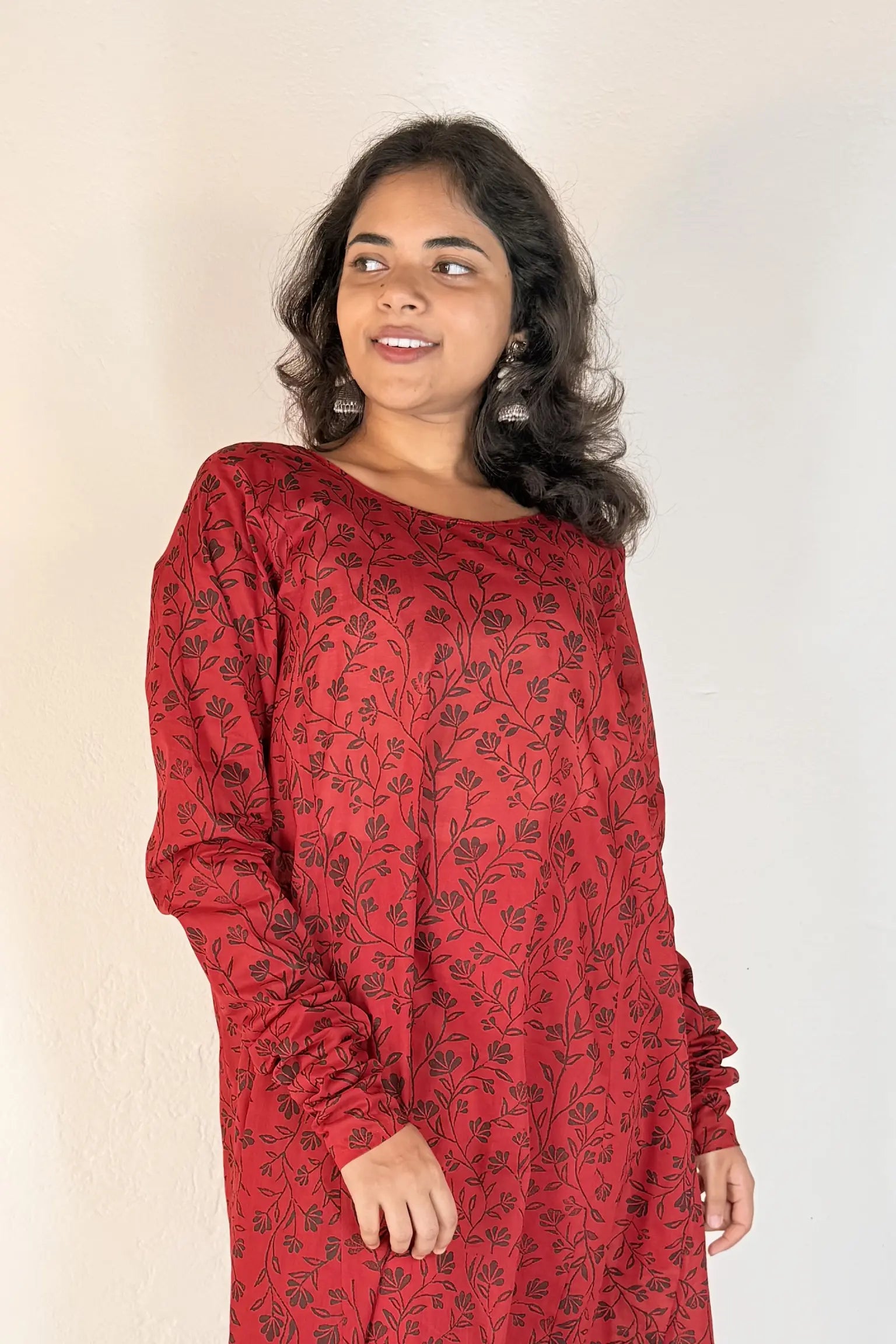 Woman wearing a red patterned dress against a plain background