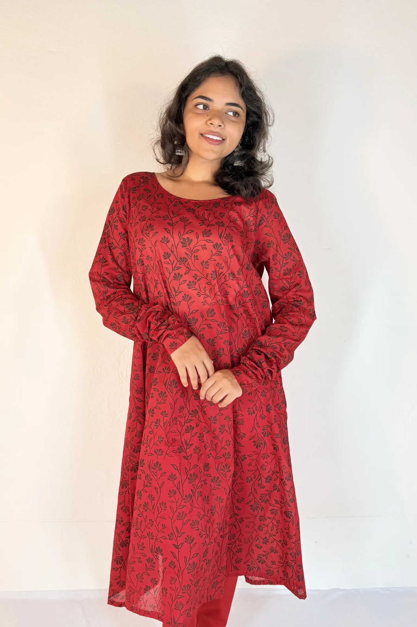 Woman wearing a red patterned dress against a white background