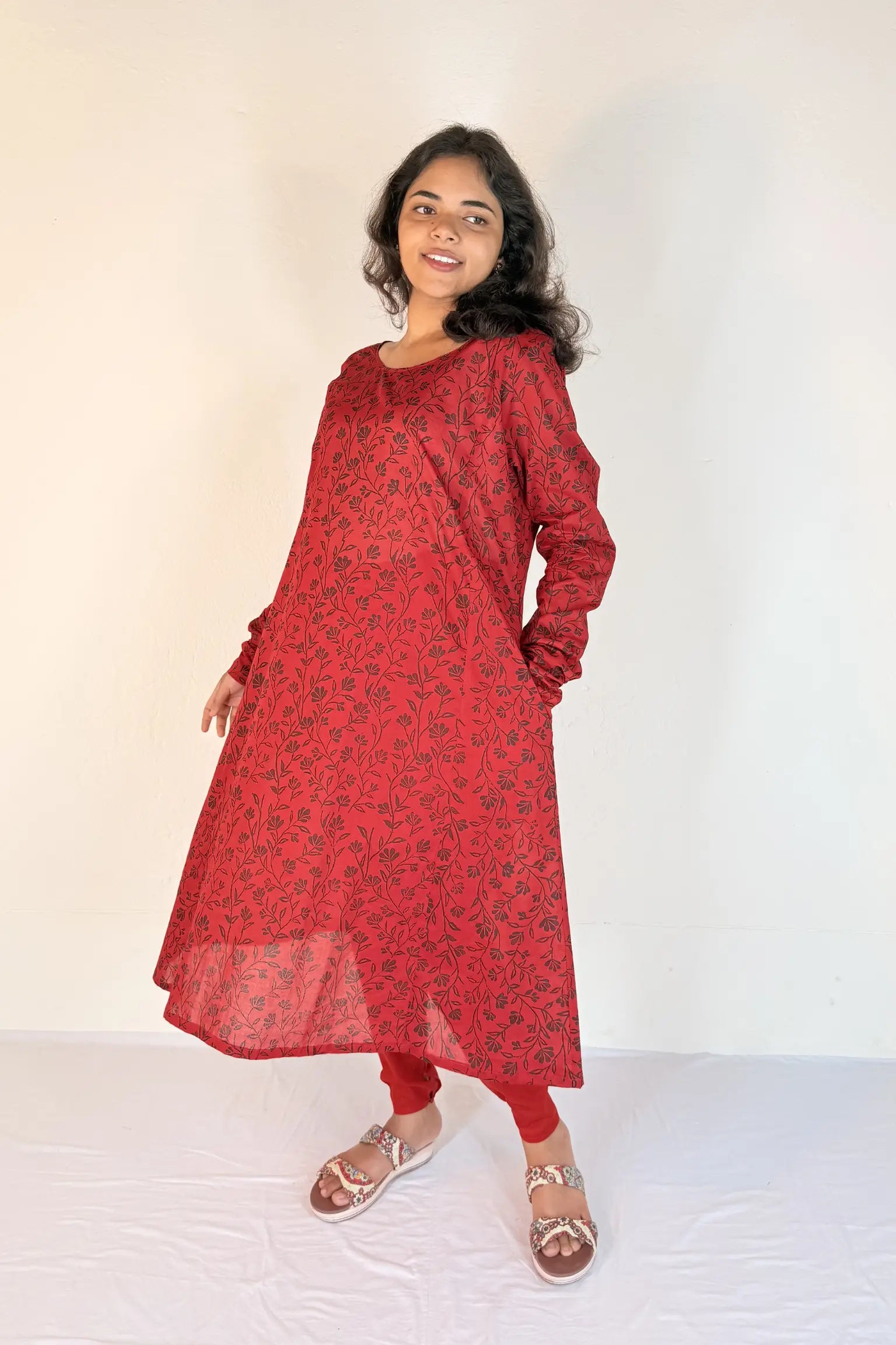 Woman wearing a red patterned dress on a white background