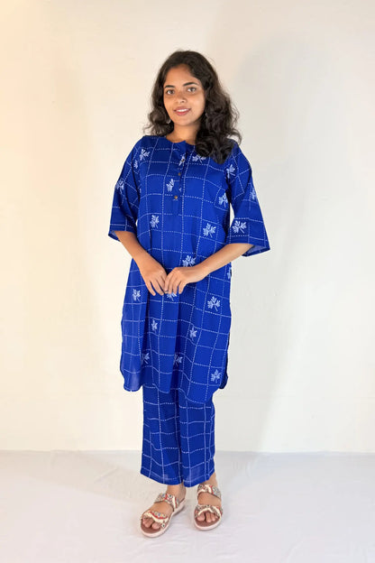 Woman wearing a blue patterned outfit against a white background