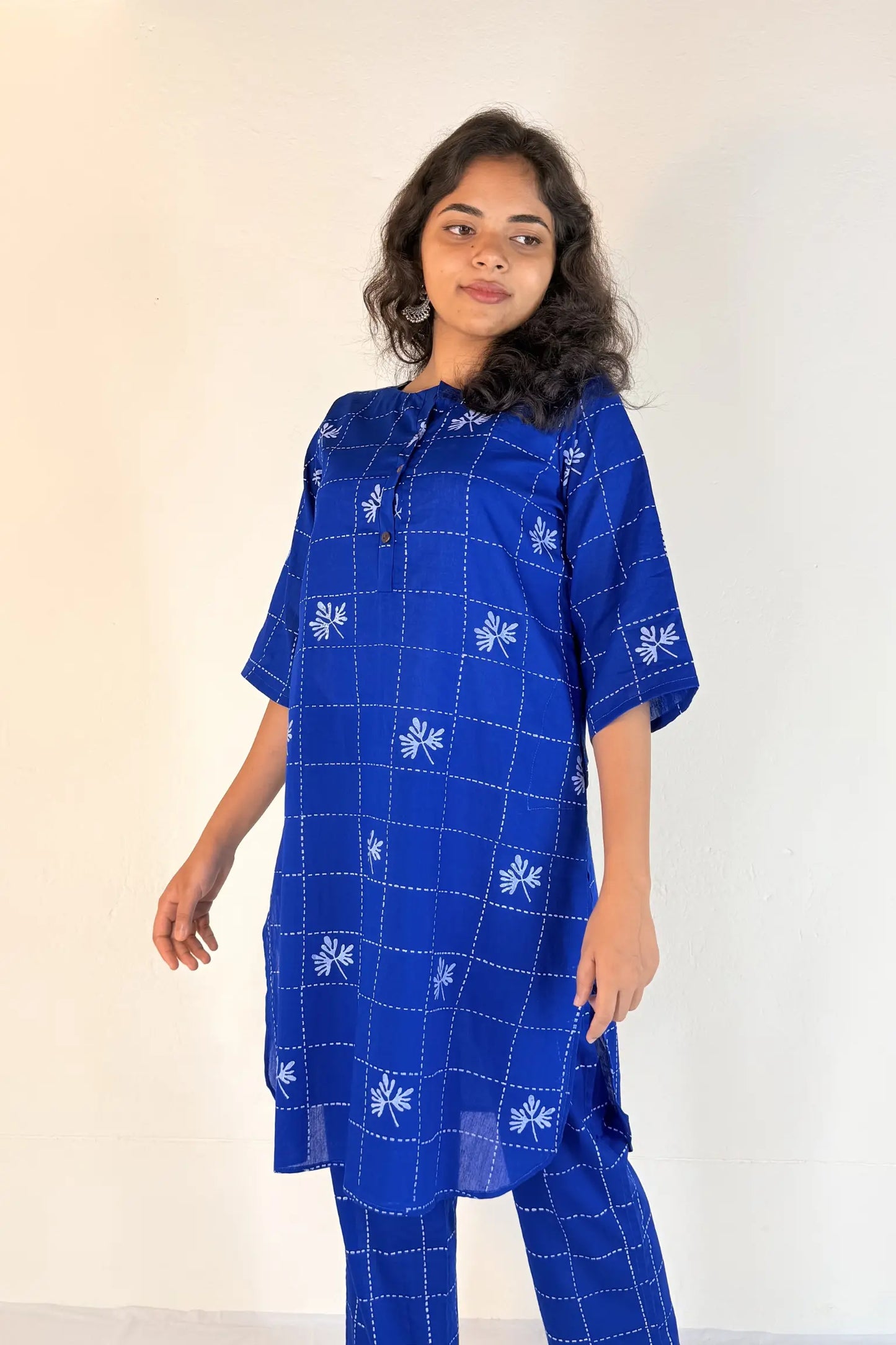 Woman wearing a blue checkered dress with white patterns against a white background