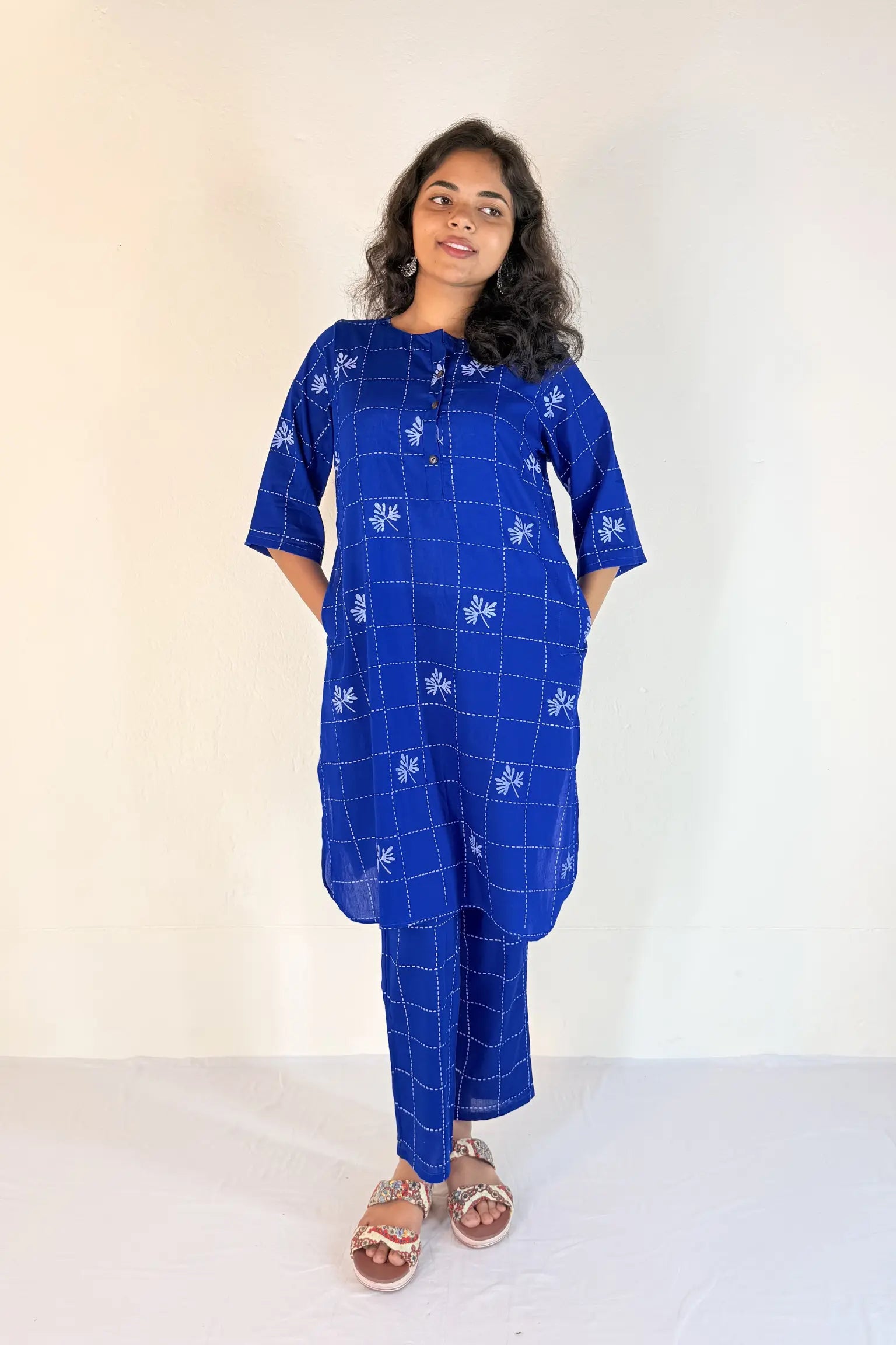 Woman wearing a blue checkered outfit with white patterns on a white background