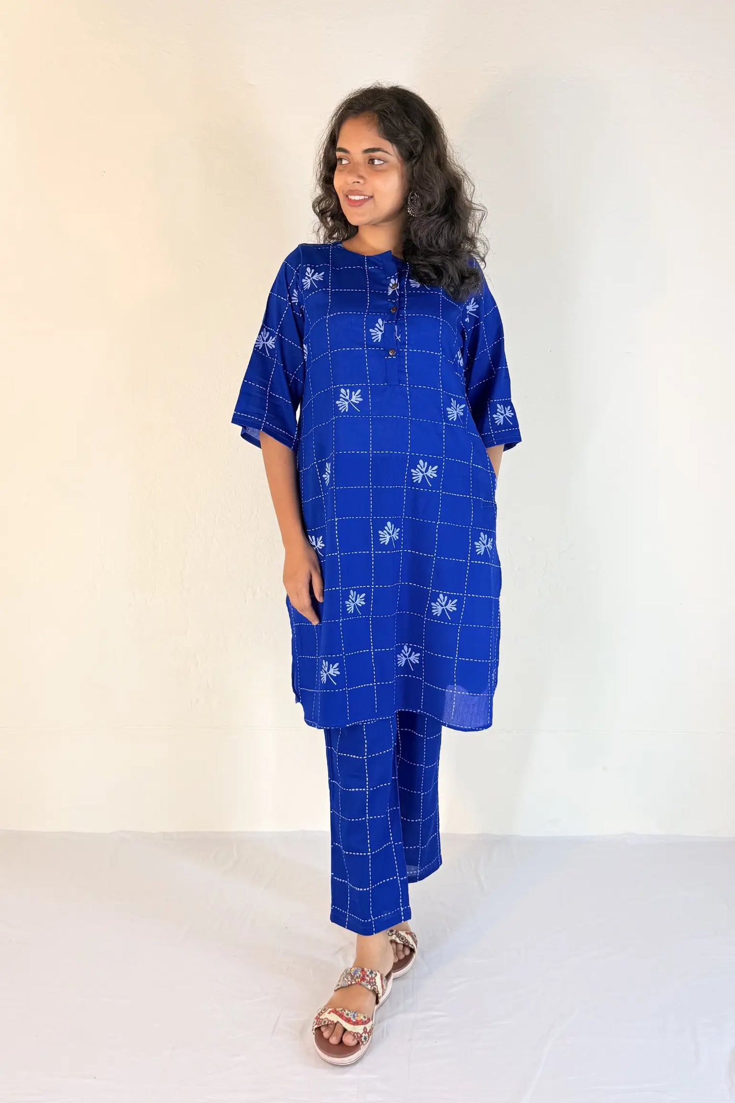 Woman wearing a blue checkered outfit with white patterns on a plain background
