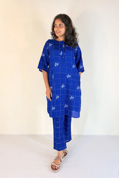 Woman wearing a blue checkered outfit with white patterns on a plain background