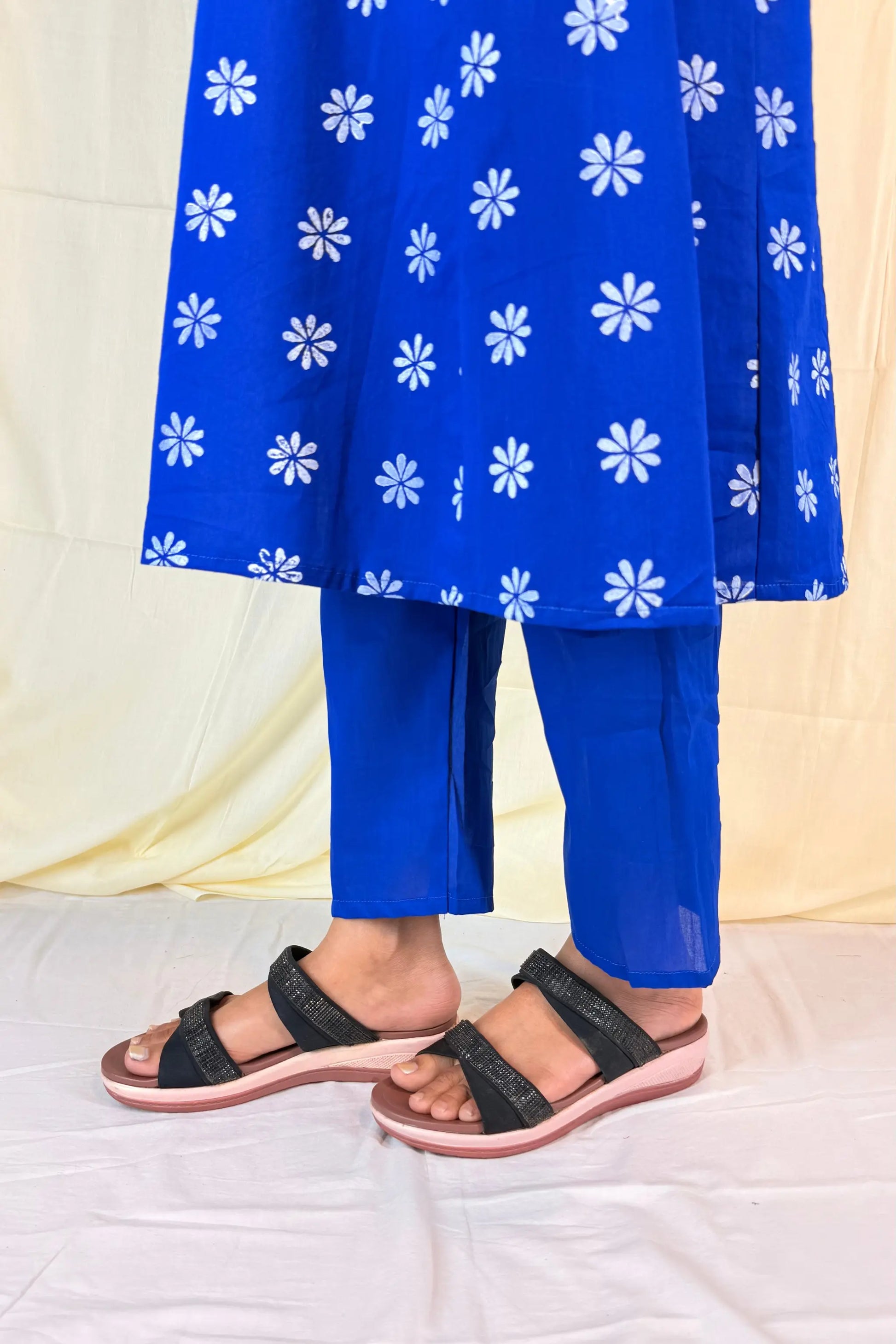 Blue floral dress with matching pants and black sandals on a white background