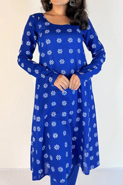 Woman wearing a blue dress with white floral patterns against a plain background