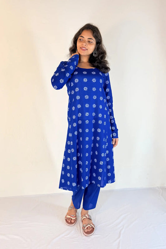 Woman wearing a blue floral dress with white flowers on a plain background