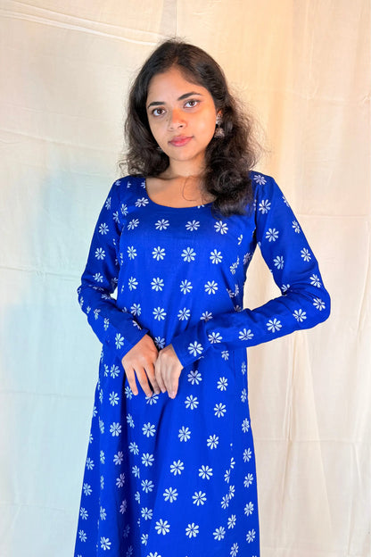Woman wearing a blue dress with white floral patterns against a neutral background