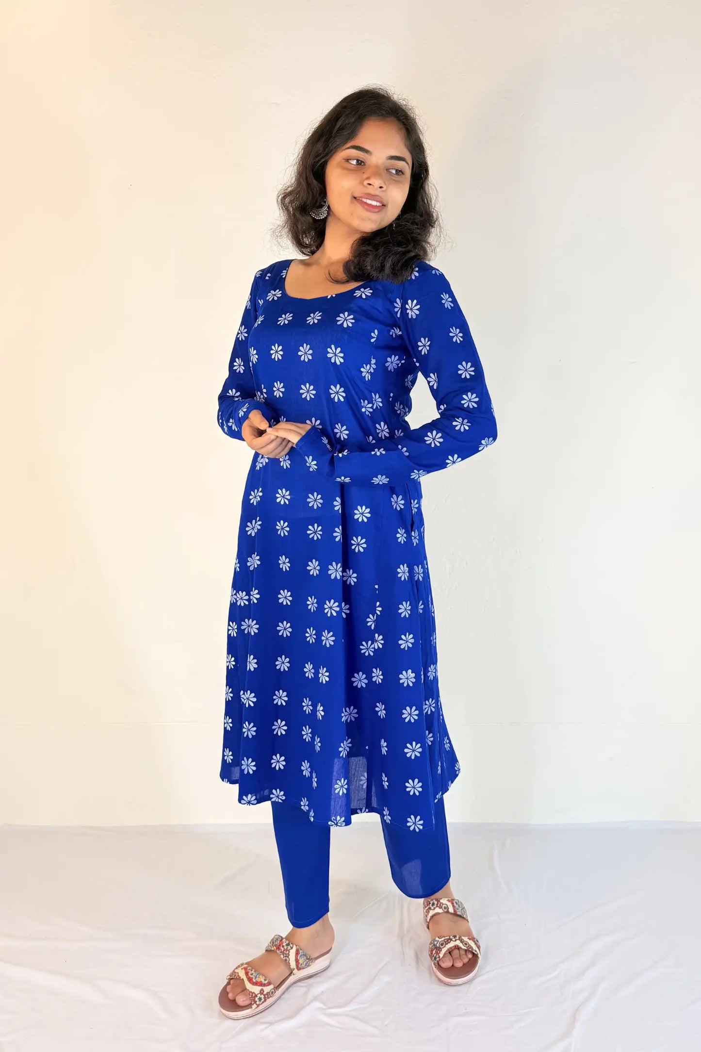 Woman wearing a blue floral dress with white flowers on a plain background